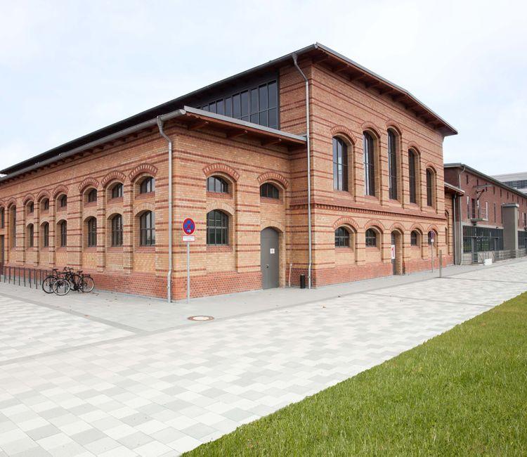 Ziegelbau mit abgerundeten Fenstern und moderner Umgebung