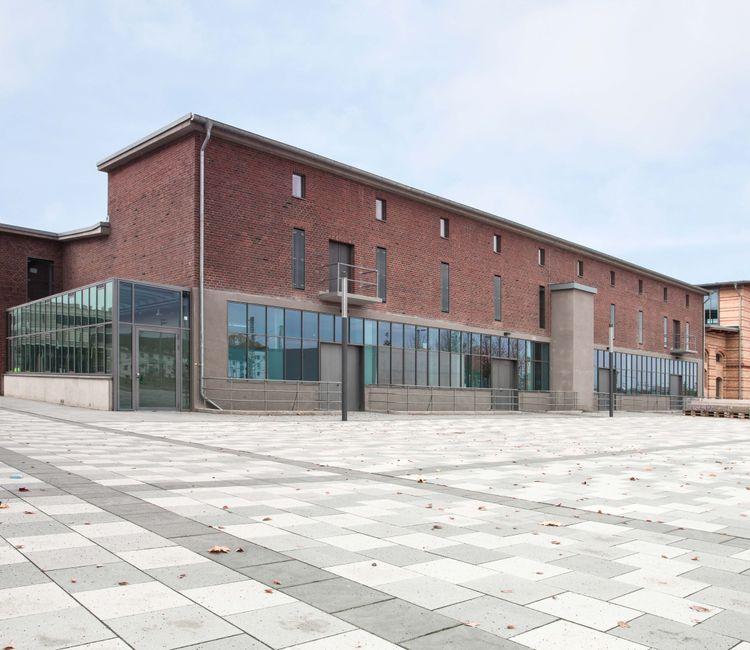 Ansicht des Gebäudekomplexes mit Kombination aus Backstein und modernen Glaselementen
