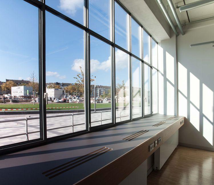 Innenansicht eines modernen Arbeitsbereichs mit bodentiefen Fenstern und Blick ins Freie.