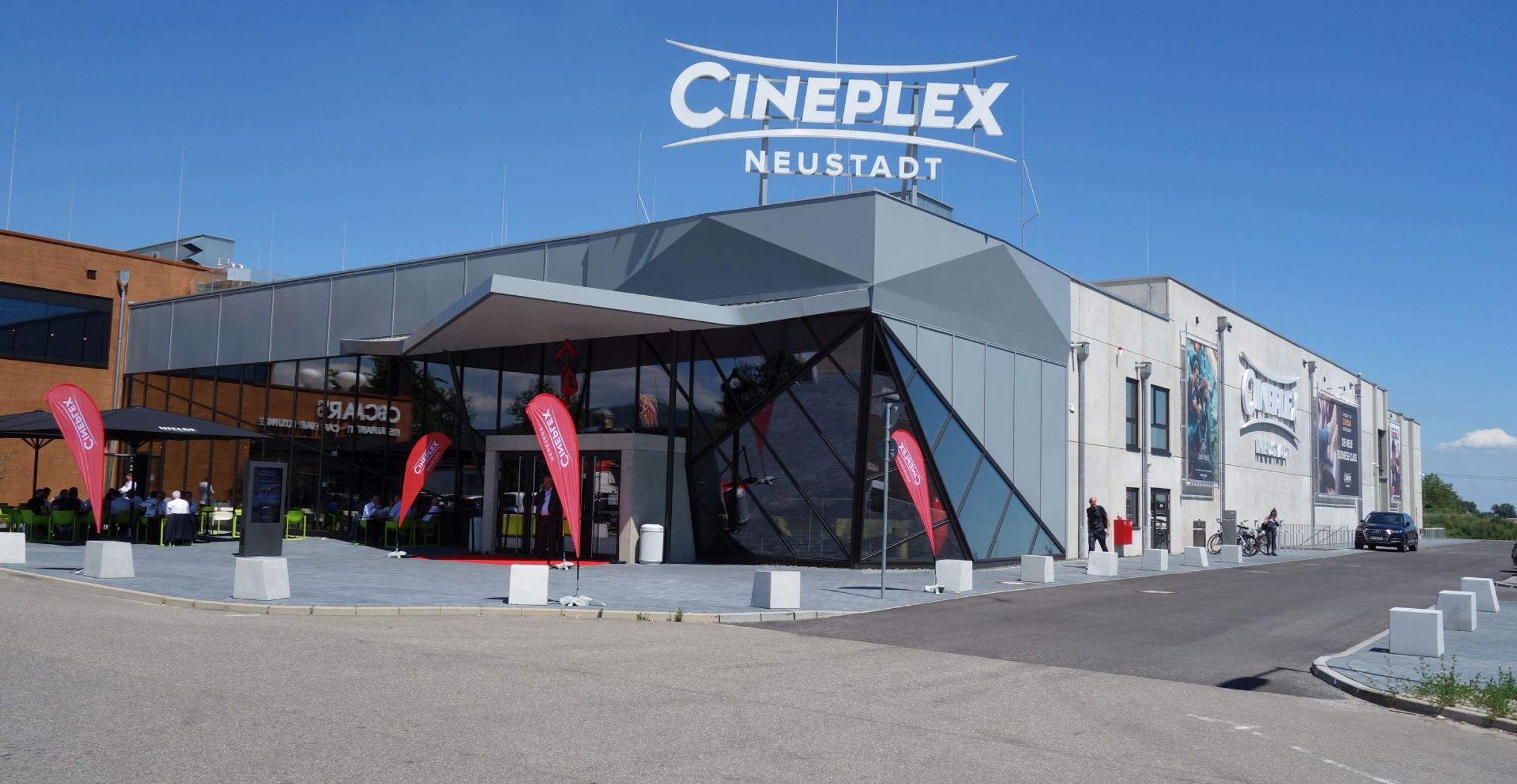Außenansicht des Cineplex Neustadt mit der markanten Glasfassade und dem Schriftzug auf dem Dach.
