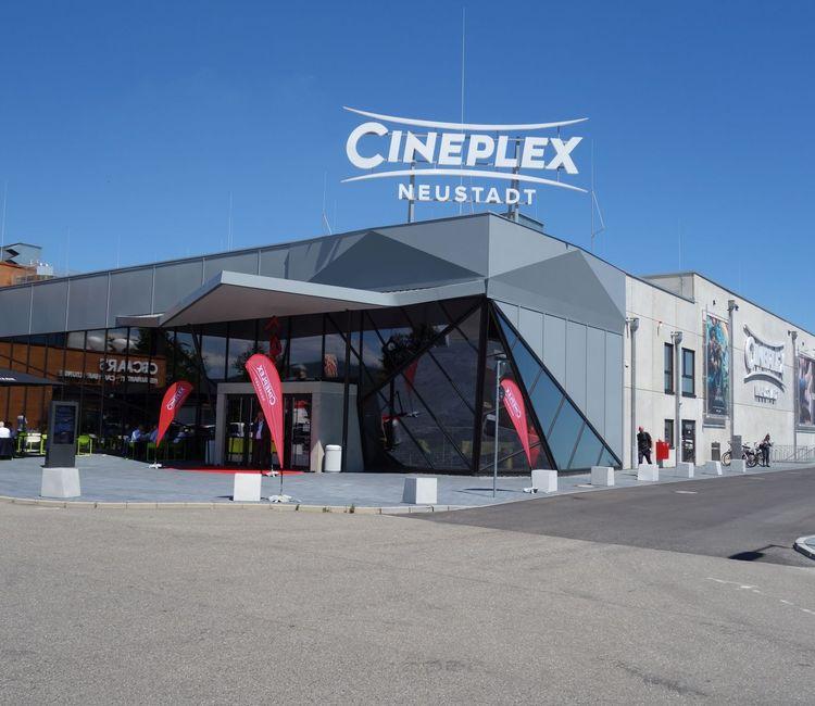 Außenansicht des Cineplex Neustadt mit der markanten Glasfassade und dem Schriftzug auf dem Dach.