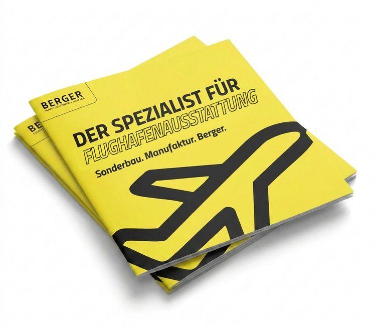 Zwei gelbe Kataloge von Berger mit schwarzem Flugzeugsymbol und der Aufschrift 'DER SPEZIALIST FÜR FLUGHAFENMÖBEL Sonderbau. Manufaktur. Berger.'